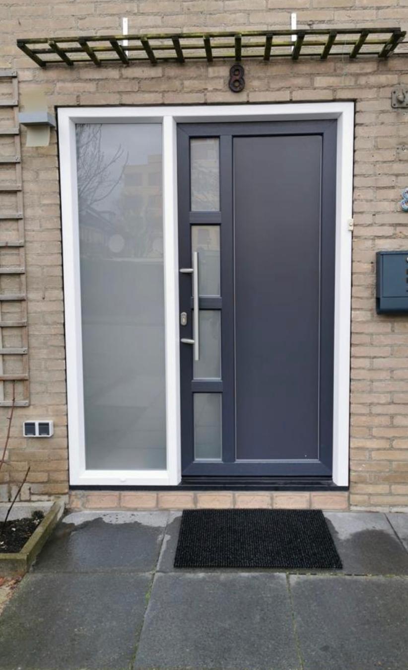 Moderne voordeur in antraciet met verticale glaspanelen en groot zijlicht